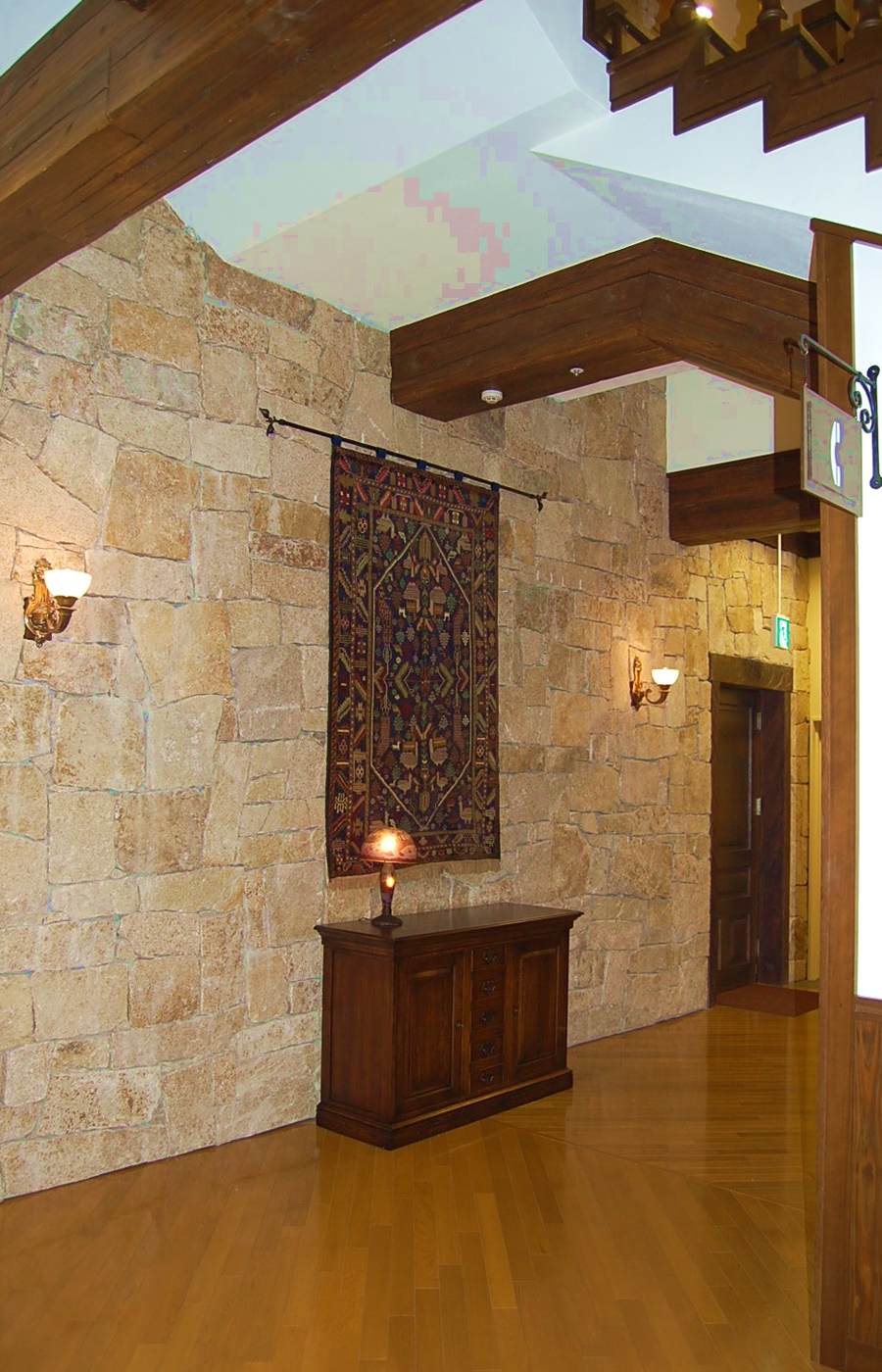 石の壁面に絨毯を飾り、サイドボードをその下に配置。